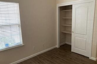 9872 N Woodrow Ave, Fresno, CA 93720 - unfurnished bedroom with baseboards, a closet, and dark wood finished floors