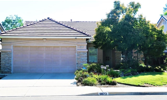 9872 N Woodrow Ave, Fresno, CA 93720 - view of front facade with stone siding, a tiled roof, and driveway