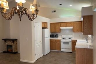 9872 N Woodrow Ave, Fresno, CA 93720 - kitchen featuring white appliances, brown cabinets, under cabinet range hood, a chandelier, and a sink