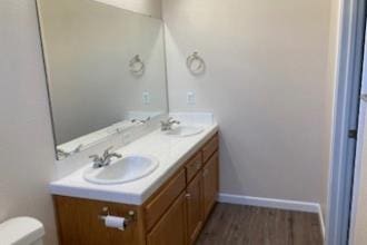 9872 N Woodrow Ave, Fresno, CA 93720 - bathroom featuring double vanity, toilet, wood finished floors, and baseboards