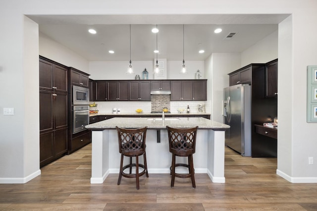3771 Wrenwood Ave, Clovis, CA 93619 - kitchen featuring stainless steel appliances, under cabinet range hood, light wood-type flooring, dark brown cabinets, and backsplash