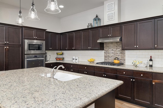 3771 Wrenwood Ave, Clovis, CA 93619 - kitchen featuring stainless steel appliances, a sink, under cabinet range hood, light stone counters, and hanging light fixtures