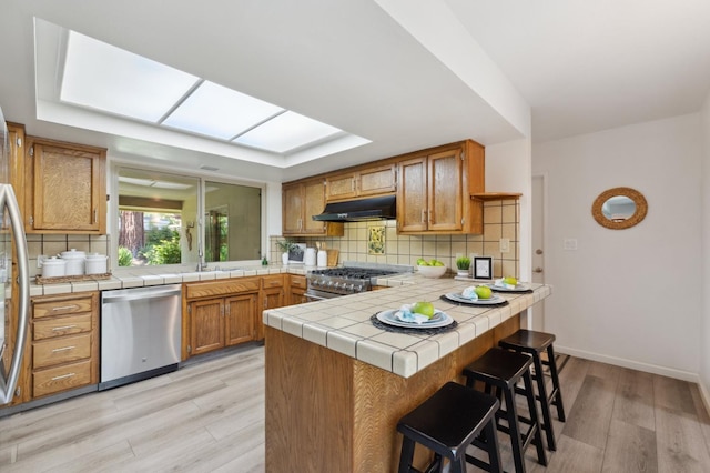 3244 W Fremont Ave, Fresno, CA 93711 - kitchen featuring stainless steel appliances, under cabinet range hood, decorative backsplash, and a peninsula