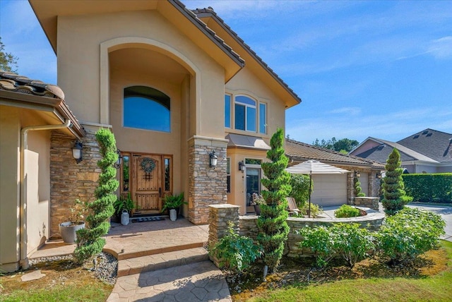 2707 W Menlo Ave, Fresno, CA 93711 - doorway to property featuring stucco siding, stone siding, a garage, and a tiled roof