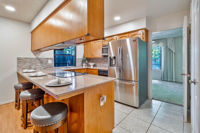 4633 N Glenn Ave, Fresno, CA 93704 - kitchen with appliances with stainless steel finishes, a peninsula, a sink, tasteful backsplash, and a kitchen bar