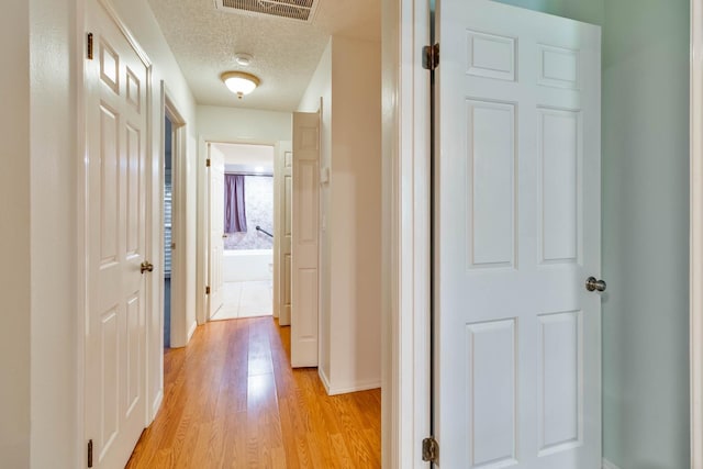4633 N Glenn Ave, Fresno, CA 93704 - hall with light wood-style floors, a textured ceiling, and baseboards