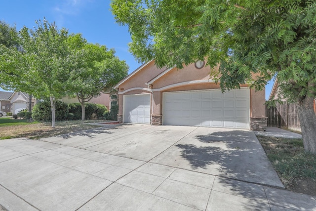 6674 E Alta Ave, Fresno, CA 93727 - view of property hidden behind natural elements featuring stucco siding, concrete driveway, stone siding, and a garage