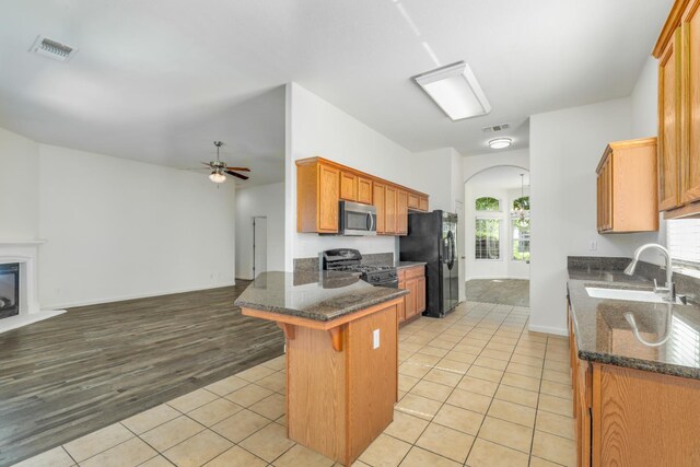 6674 E Alta Ave, Fresno, CA 93727 - kitchen with stainless steel microwave, gas stove, black refrigerator with ice dispenser, a sink, and a peninsula