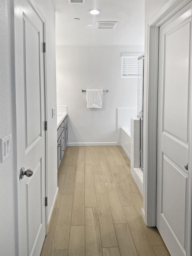 922 Winchell Way W, Madera, CA 93636 - bathroom featuring wood finished floors, a bath, vanity, baseboards, and a shower stall