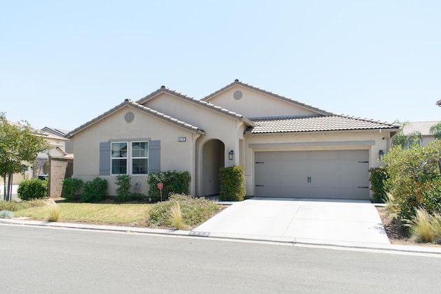 6379 W Northdale Ave, Fresno, CA 93723 - mediterranean / spanish-style house with stucco siding, an attached garage, driveway, and a tile roof