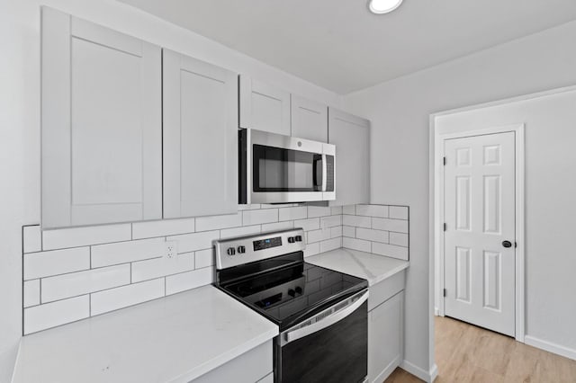 3877 N Ezie, Fresno, CA 93727 - kitchen with stainless steel appliances, backsplash, light wood finished floors, light stone counters, and baseboards