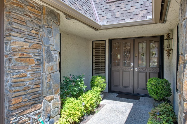 6772 N Wembley Dr, Fresno, CA 93711 - property entrance featuring a shingled roof, stucco siding, and stone siding