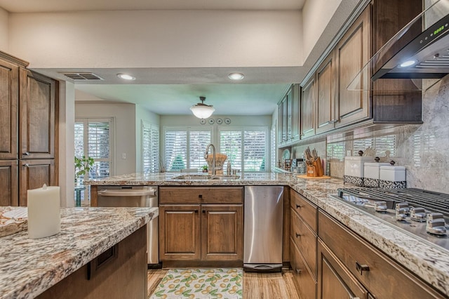 6772 N Wembley Dr, Fresno, CA 93711 - kitchen with a sink, exhaust hood, stainless steel appliances, a peninsula, and light stone counters