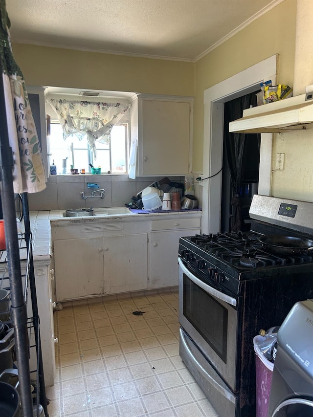 2121 E Hammond Ave, Fresno, CA 93703 - kitchen featuring gas range, crown molding, tile counters, custom range hood, and washer / dryer