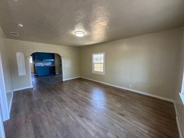 3023 E White Ave, Fresno, CA 93701 - unfurnished room with arched walkways, baseboards, dark wood-style flooring, and a textured ceiling