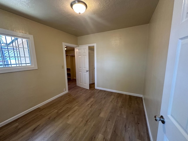 3023 E White Ave, Fresno, CA 93701 - unfurnished bedroom with wood finished floors, a textured ceiling, baseboards, a closet, and a walk in closet