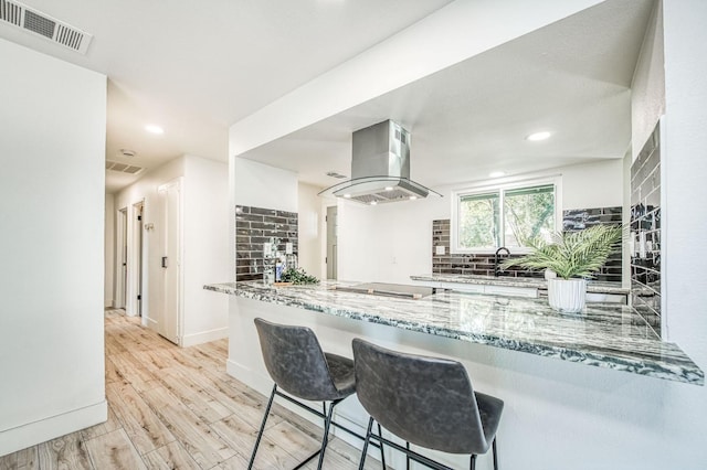 17367 Camden Dr, Madera, CA 93638 - kitchen featuring island exhaust hood, tasteful backsplash, light stone countertops, a sink, and recessed lighting