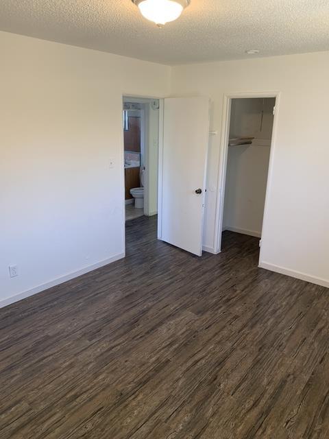 3127 E Mckenzie, Fresno, CA 93702 - unfurnished bedroom with dark wood-type flooring, a closet, baseboards, and a textured ceiling