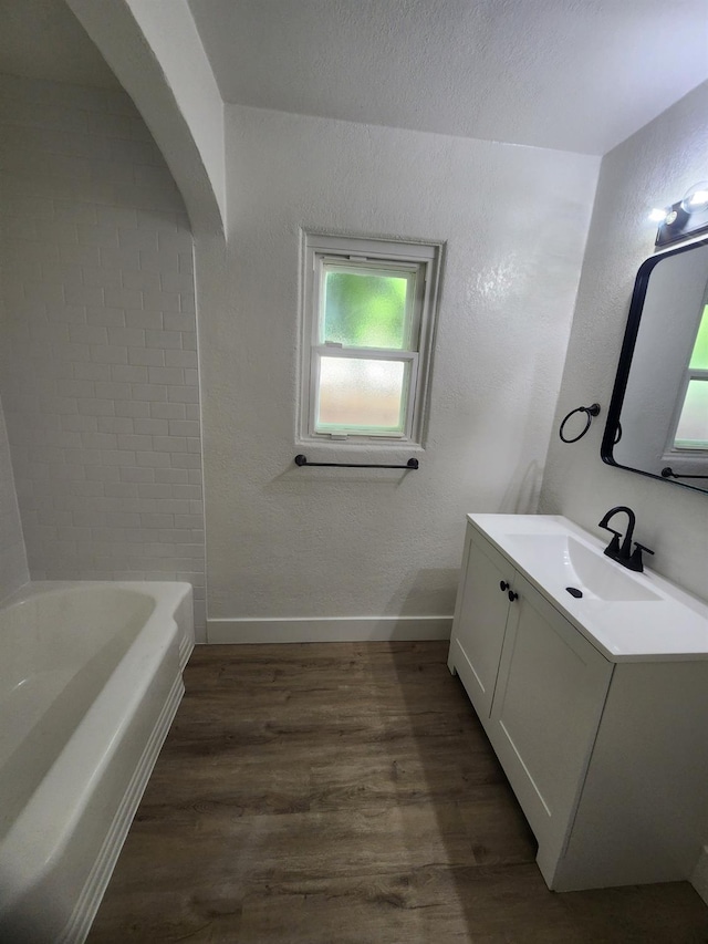 4754 E Andrews Ave, Fresno, CA 93726 - full bathroom featuring vanity, wood finished floors, a tub, baseboards, and a textured wall