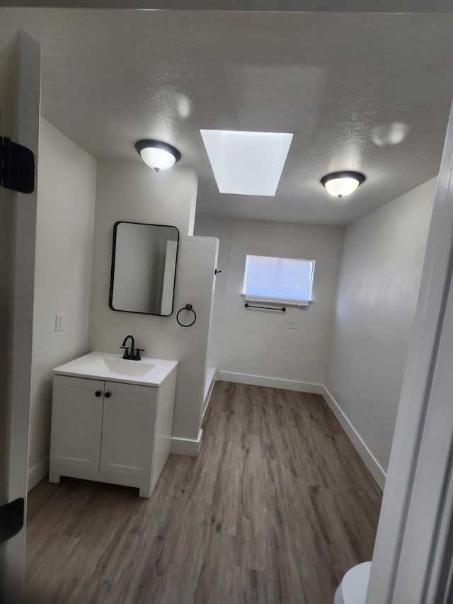 4754 E Andrews Ave, Fresno, CA 93726 - bathroom with a skylight, vanity, wood finished floors, walk in shower, and toilet