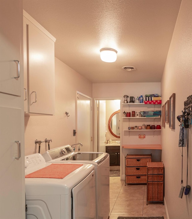 1720 W Barstow Ave, Fresno, CA 93711 - washroom featuring washing machine and clothes dryer, cabinet space, light tile patterned flooring, and a textured ceiling