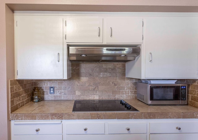 1720 W Barstow Ave, Fresno, CA 93711 - kitchen featuring stainless steel microwave, under cabinet range hood, tile countertops, black electric cooktop, and tasteful backsplash