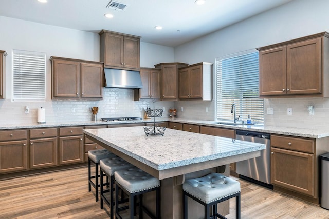 2054 N Laverne Ave, Fresno, CA 93727 - kitchen with appliances with stainless steel finishes, exhaust hood, a sink, a kitchen bar, and light wood-style floors