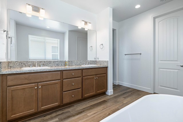 2054 N Laverne Ave, Fresno, CA 93727 - bathroom featuring wood finished floors, a freestanding tub, double vanity, baseboards, and recessed lighting