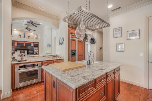 2136 E Royal Dornoch Ave, Fresno, CA 93730 - kitchen featuring stainless steel oven, ceiling fan, arched walkways, crown molding, and brown cabinets