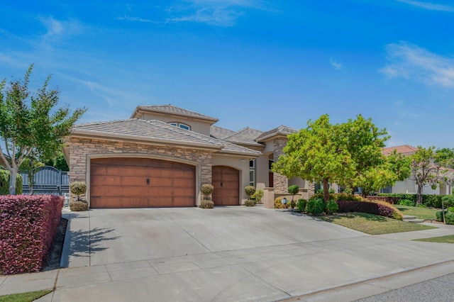 2136 E Royal Dornoch Ave, Fresno, CA 93730 - mediterranean / spanish-style home with stone siding, an attached garage, driveway, and stucco siding