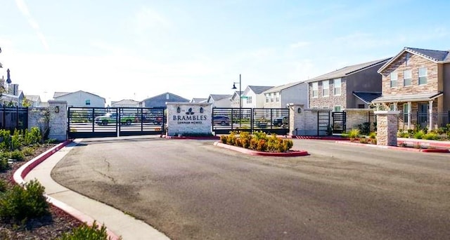 2897 E Tamarind Dr, Fresno, CA 93730 - view of asphalt road featuring a residential view, a gate, curbs, and a gated entry