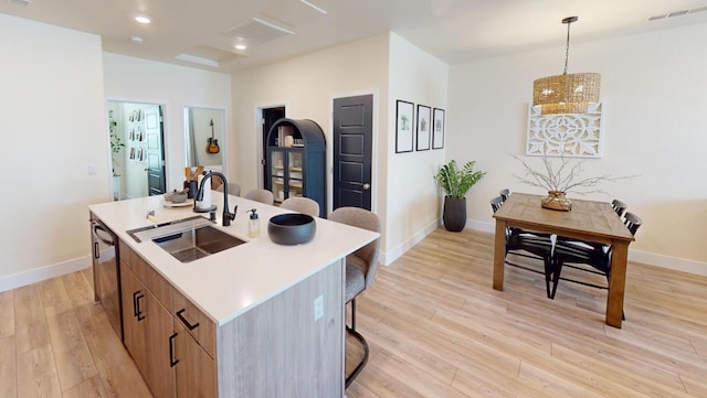 2897 E Tamarind Dr, Fresno, CA 93730 - kitchen featuring a sink, light wood-style flooring, an island with sink, baseboards, and a breakfast bar area