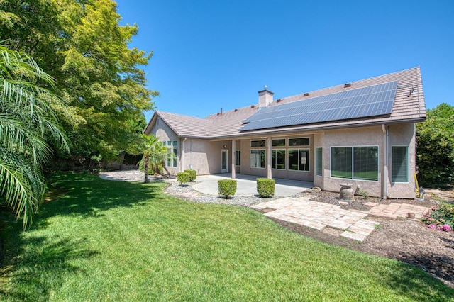 1251 E Rosemont Ln, Fresno, CA 93730 - rear view of property featuring a patio area, a yard, stucco siding, a chimney, and roof mounted solar panels