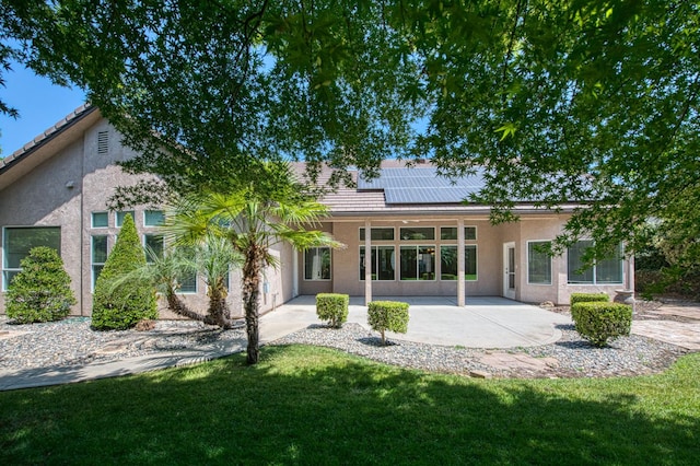 1251 E Rosemont Ln, Fresno, CA 93730 - rear view of property with stucco siding, a patio, roof mounted solar panels, and a yard