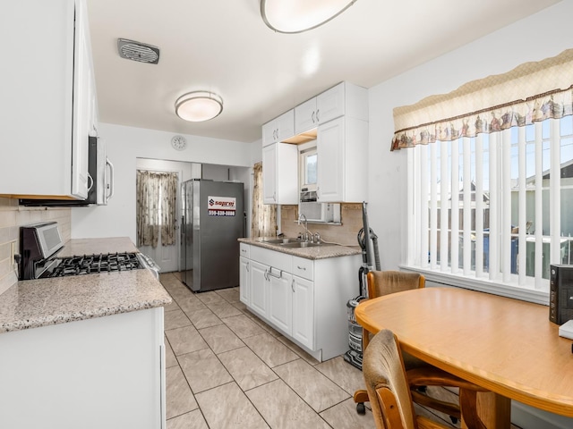 1632 W Shields Ave, Fresno, CA 93705 - kitchen with appliances with stainless steel finishes, a sink, decorative backsplash, and white cabinets