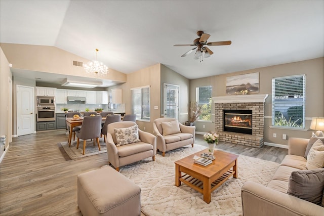 10131 N Price Ave, Fresno, CA 93730 - living room featuring vaulted ceiling, light wood-style floors, ceiling fan, a chandelier, and a brick fireplace