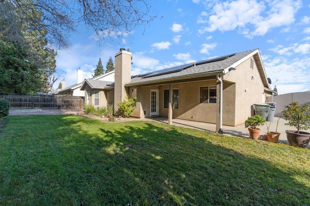10131 N Price Ave, Fresno, CA 93730 - rear view of property featuring stucco siding, a patio area, roof mounted solar panels, and a chimney