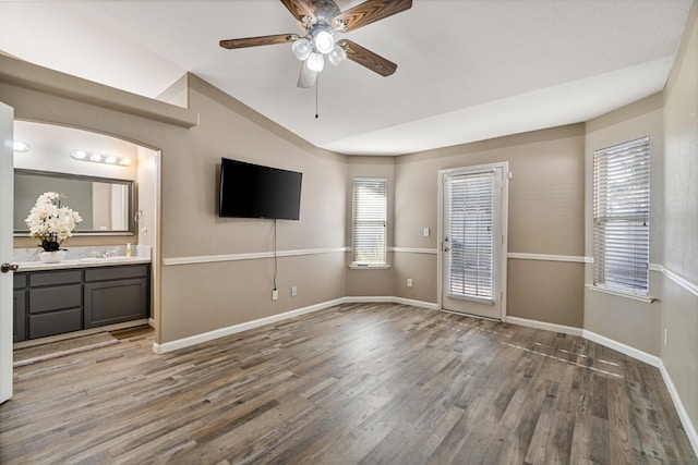 10131 N Price Ave, Fresno, CA 93730 - unfurnished living room featuring wood finished floors, ceiling fan, vaulted ceiling, baseboards, and a sink