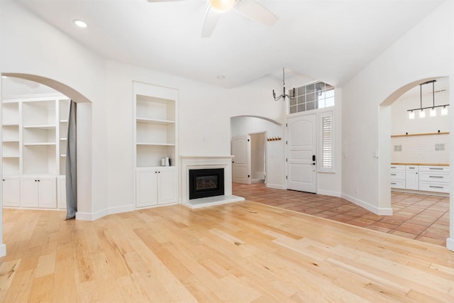 2189 W Via Delfini, Fresno, CA 93711 - unfurnished living room with light wood-type flooring, arched walkways, built in shelves, a ceiling fan, and recessed lighting