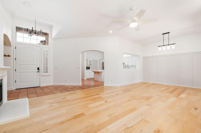 2189 W Via Delfini, Fresno, CA 93711 - foyer entrance featuring light wood-style flooring, arched walkways, a chandelier, a ceiling fan, and a fireplace with raised hearth
