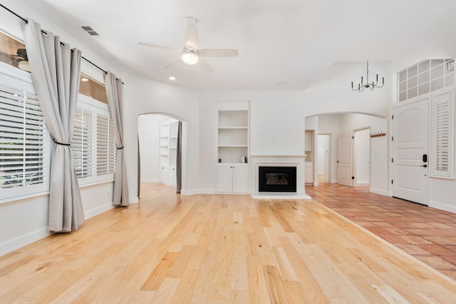 2189 W Via Delfini, Fresno, CA 93711 - unfurnished living room with arched walkways, built in shelves, a ceiling fan, a glass covered fireplace, and baseboards