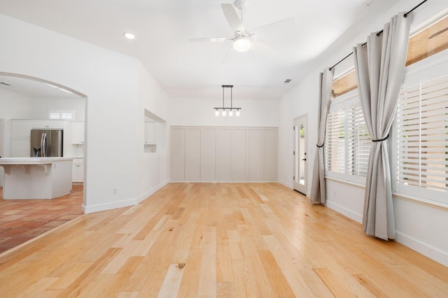 2189 W Via Delfini, Fresno, CA 93711 - empty room with light wood finished floors, ceiling fan, arched walkways, recessed lighting, and baseboards