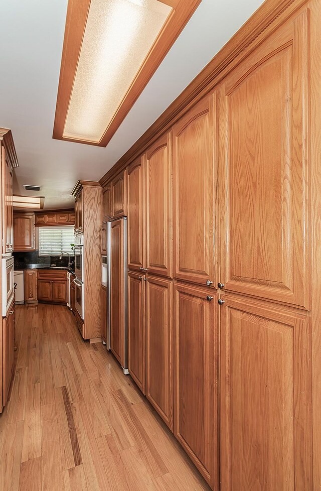 311 S Fowler Ave, Fowler, CA 93625 - kitchen with paneled built in fridge, light wood finished floors, stainless steel double oven, brown cabinetry, and dark countertops