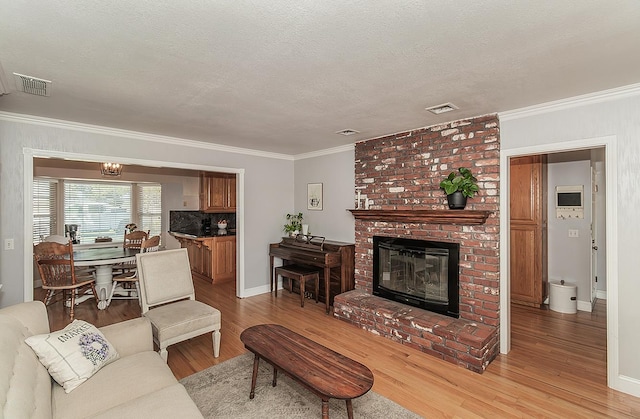 311 S Fowler Ave, Fowler, CA 93625 - living area featuring light wood finished floors, ornamental molding, a fireplace, baseboards, and a textured ceiling