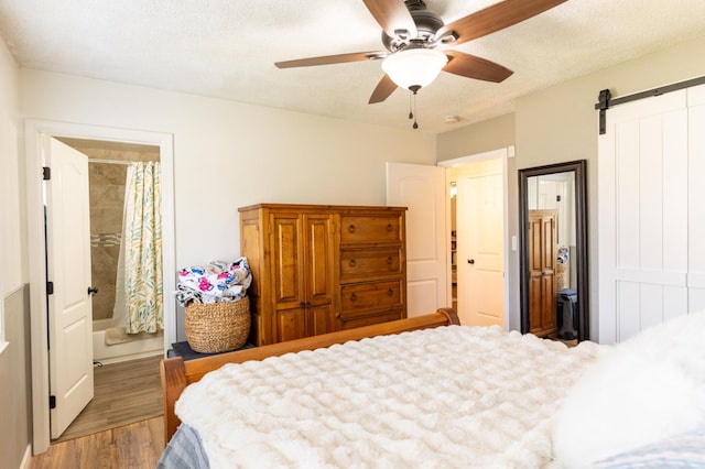 101 S Princeton Ave, Coalinga, CA 93210 - bedroom with light wood-style floors, a barn door, a ceiling fan, ensuite bathroom, and a textured ceiling