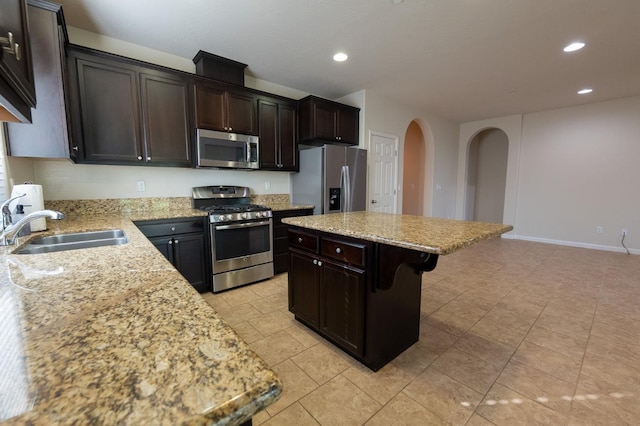 3083 N Stanley Ave, Fresno, CA 93737 - kitchen featuring stainless steel appliances, arched walkways, a sink, a kitchen bar, and a kitchen island