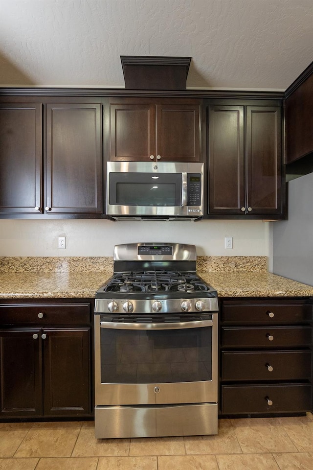 3083 N Stanley Ave, Fresno, CA 93737 - kitchen featuring stainless steel appliances, dark brown cabinetry, light tile patterned flooring, and light stone countertops