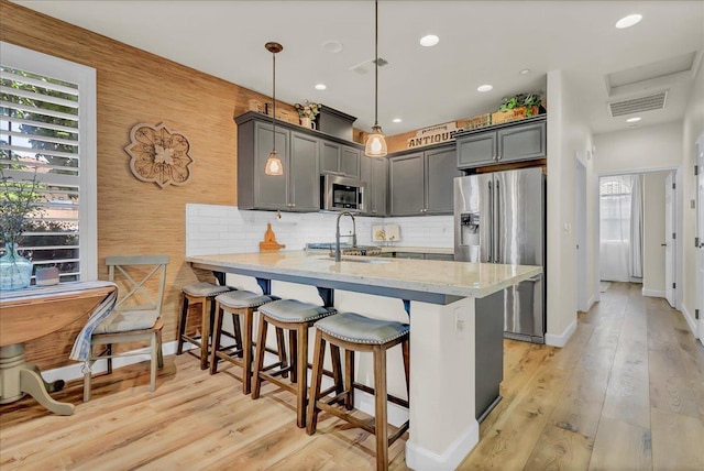 1281 W Walter Ave Unit 15, Fowler, CA 93625 - kitchen featuring appliances with stainless steel finishes, a peninsula, a breakfast bar, light wood-type flooring, and recessed lighting