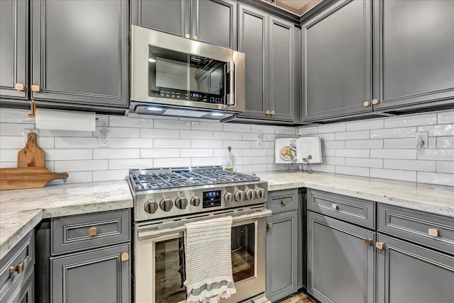 1281 W Walter Ave Unit 15, Fowler, CA 93625 - kitchen with appliances with stainless steel finishes, backsplash, gray cabinetry, and light stone countertops