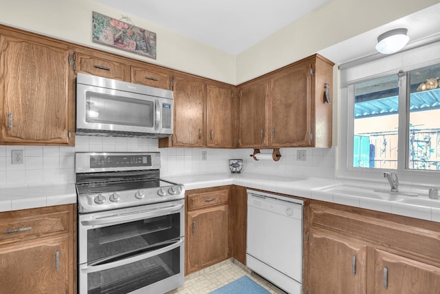 5072 N Forkner Ave, Fresno, CA 93711 - kitchen with appliances with stainless steel finishes, backsplash, brown cabinetry, and a sink